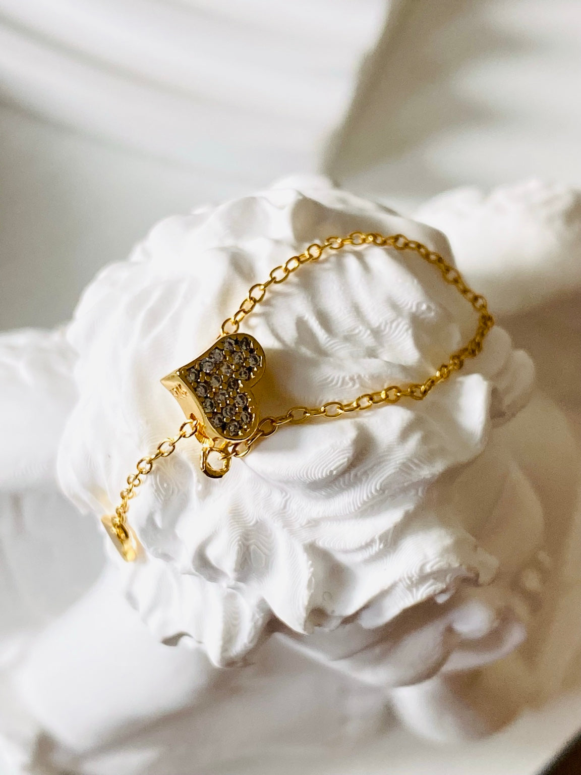 Gold heart chain ring close-up on white sculpture